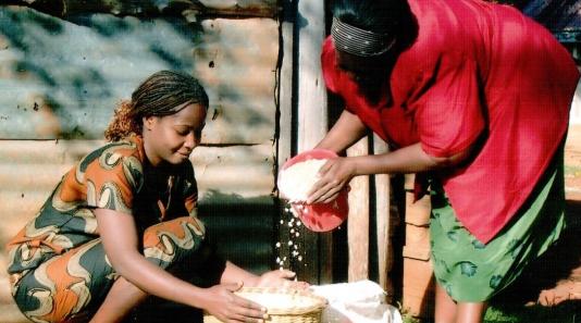 Two Kenyan women pouring grain