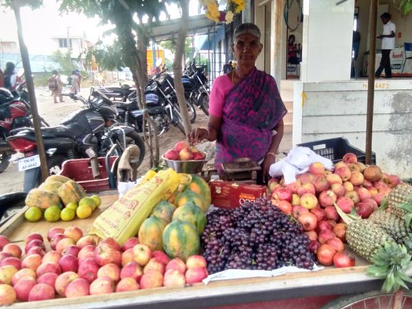 An image of a woman standing behind a fruit stall