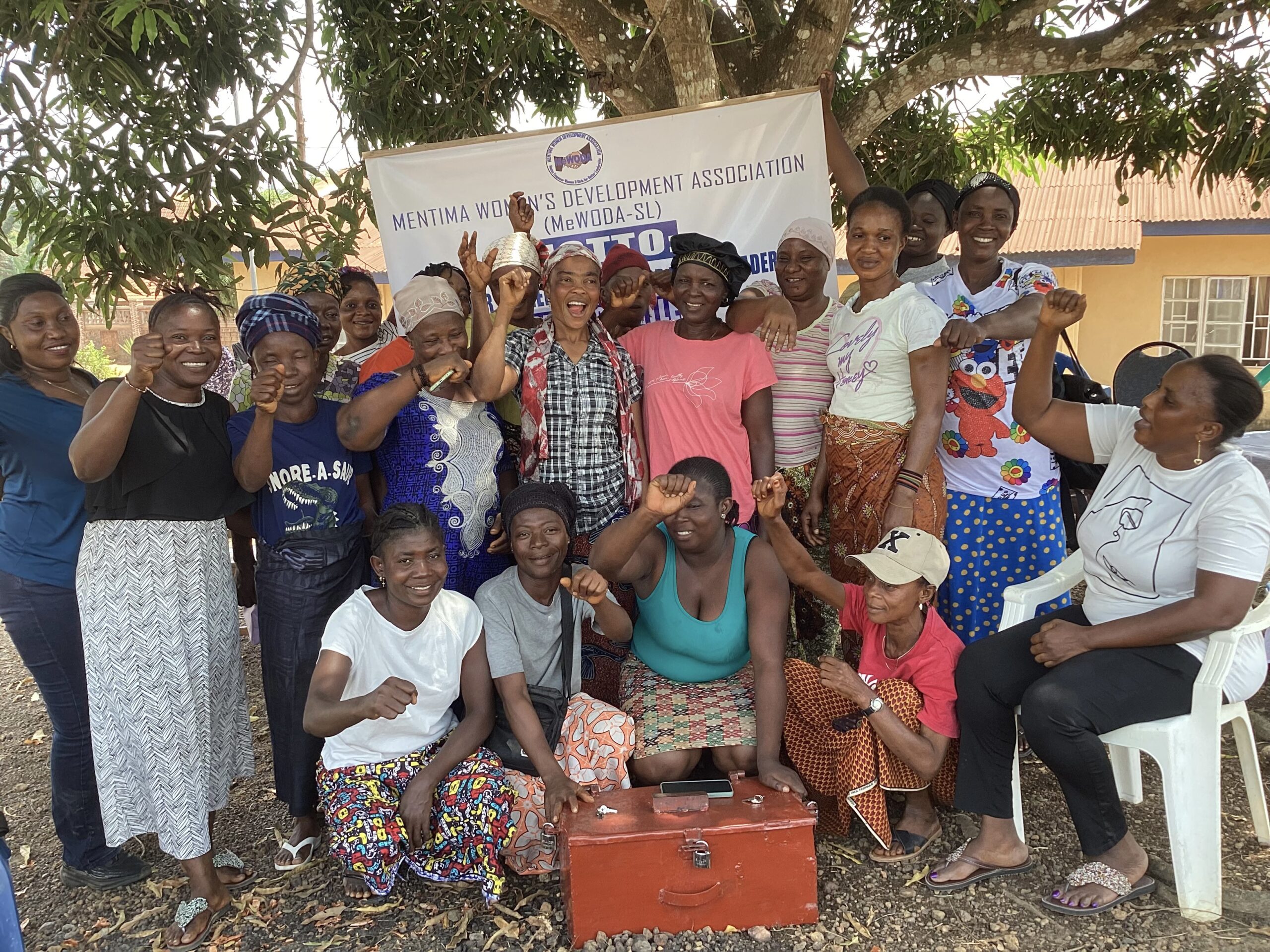 A large group of women stand in front of a red, metal box.
