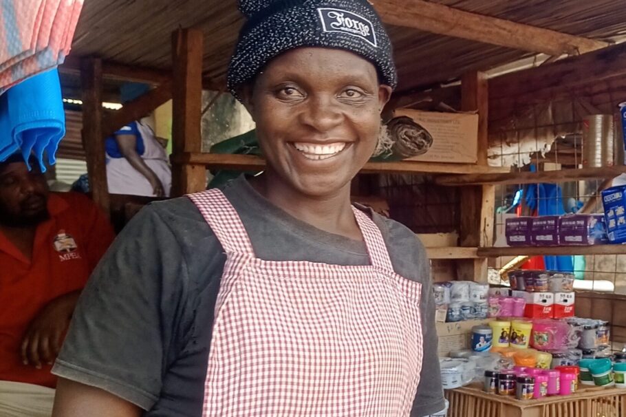 A woman stands in front of her mobile kiosk. The kiosk includes shelves with multi colored canisters of products.